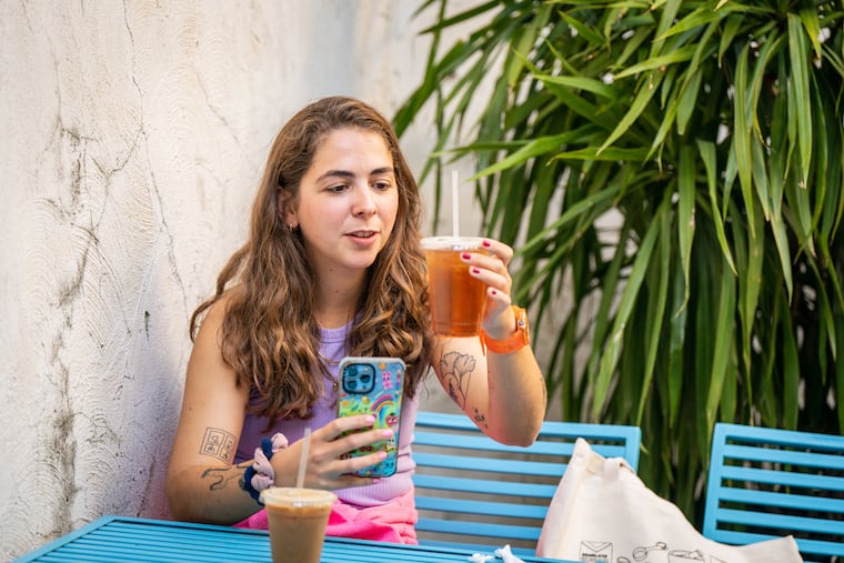 Gloria Sullivan — a.k.a. @_gloyoyo_ on TikTok — is reviewing 100 Philadelphia coffee shops for her nearly 200K followers over the next year. She is seen filming a review at Vault + Vine in East Falls, her ninth stop.