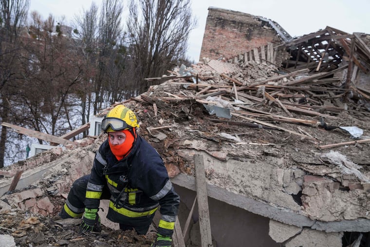 A rescue worker climbs onto the roof of apartment building damaged after a Russian strike on Kyiv, Ukraine, on Saturday, Dec. 27, 2025.