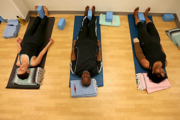 Jennifer Hook, 60, of West Philadelphia, Frank Garnes, 66, of Southwest Philadelphia, and Charmette Jackson, 71, left to right, participate in a yoga class held at the Hospital of the University of Pennsylvania. DAVID MAIALETTI / Staff Photographer