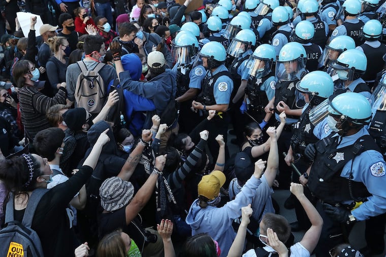 Police officers guarding the Trump International Hotel & Tower hold back protesters during a rally and march to remember the May 25 killing of George Floyd by a Minneapolis police officer, in the Loop Saturday, May 30, 2020, in Chicago, Ill.