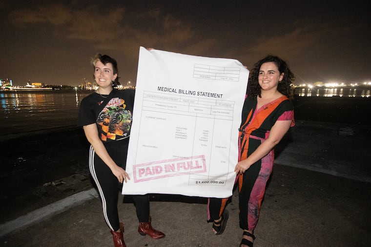 A group raised more than $15,000 to buy medical debt worth $1.6 million. Instead of cashing in on the debt, they forgave it, helping more than 1,700 Philadelphians. They celebrated with a ceremonial debt burning at the pier by Walmart on Aug. 25, 2023. Lou Garner (left) and Claire Hirschberg hold up the medical bill prior to the dept burning. celebration.