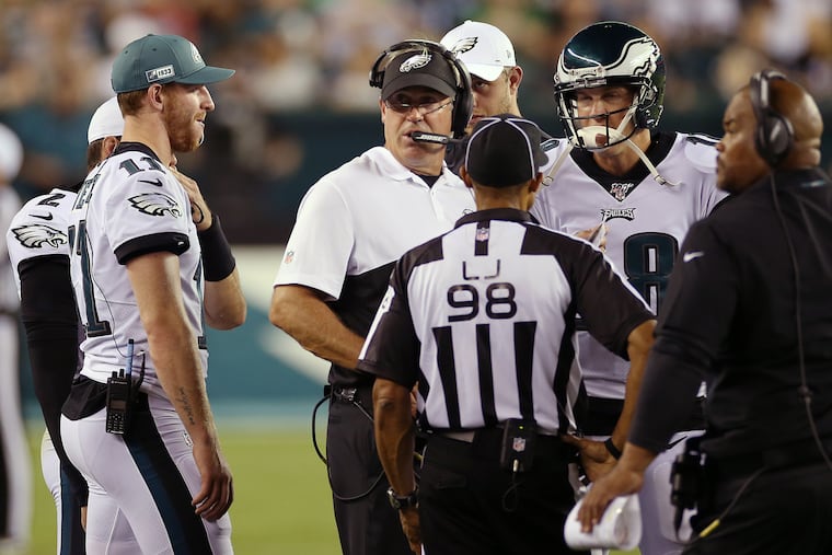 Eagles quarterback Carson Wentz (11) and quarterback Josh McCown (18) huddle with head coach Doug Pederson as he waits for officials to review a call during a preseason game against the Baltimore Ravens at Lincoln Financial Field in South Philadelphia on Thursday, Aug. 22, 2019.