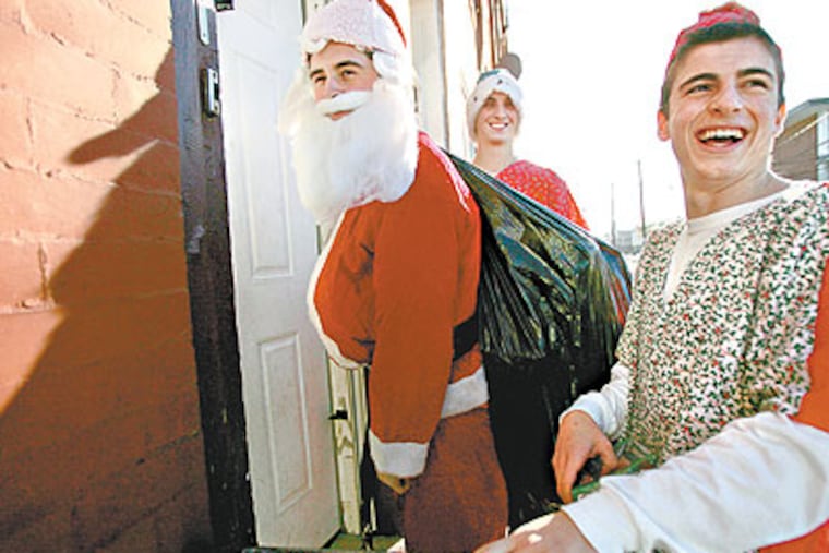 Michael DeFeo as Santa and his elves, Charles Foltz (middle) and Mark Casale (right), wait for an answer at a door on 22nd Street so they can deliver presents. (David Swanson / Staff Photographer)