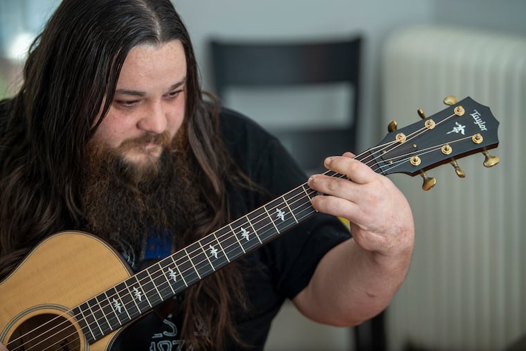 John Foisy plays the guitar at his home in Perkasie. After a car accident John suffered a major injury to his left hand, losing his pinkie and palm and fracturing every finger and thumb.