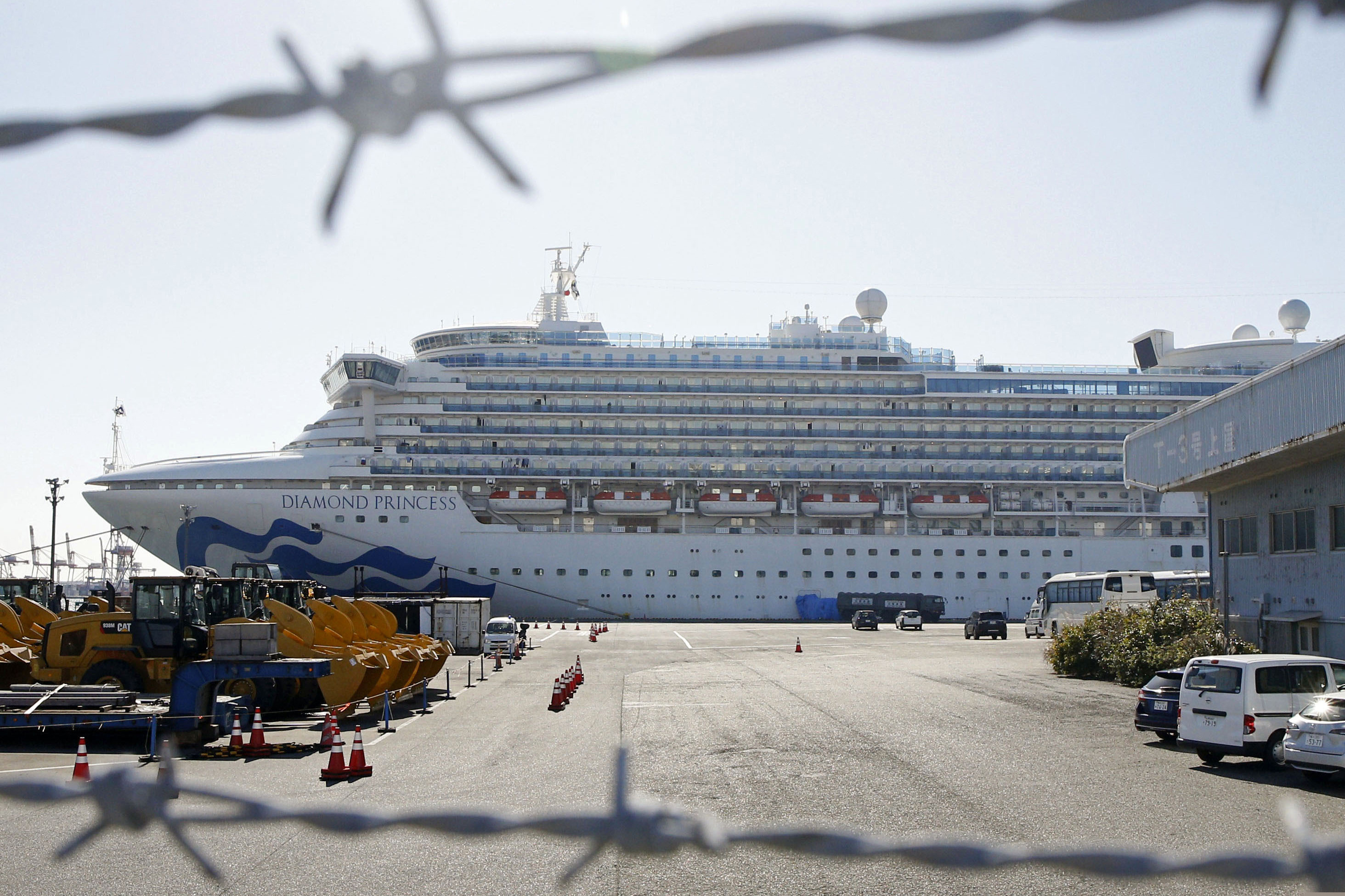 The quarantined ship Diamond Princess is pictured through barbed wire at Yokohama port in Yokohama, near Tokyo Monday, Feb. 17, 2020. Japanese officials have confirmed 99 more people infected by the new virus aboard the ship, the Health Ministry said Monday.