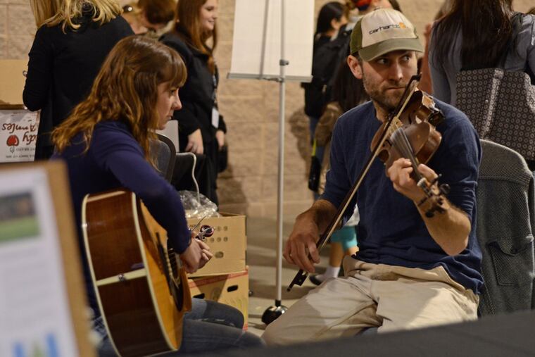 Jen Smith (left) and Nikolai Fox treat patrons to old style bluegrass music at their Temple Fox School of Business Consulting stand. ( Richard Kauffman / Staff Photographer )