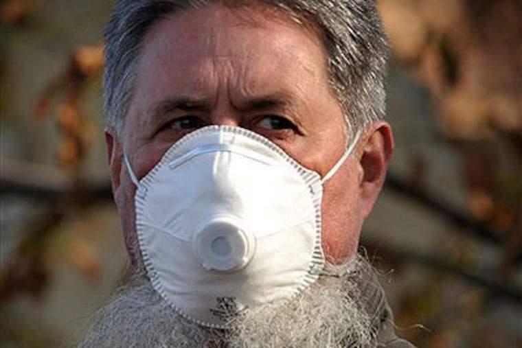 A local resident wears a protective mask as streets are covered by toxic red sludge in Devecser, Hungary, on Wednesday. (AP Photo / Bela Szandelszky)
