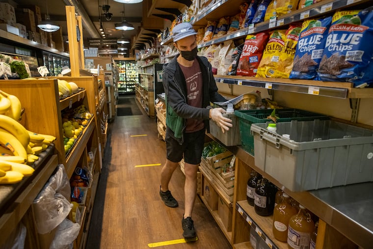 Grocery clerk Matt Sawyer organizes containers used to keep home-delivery and curbside pickup items together at Weavers Way Co-op in Philadelphia's Mount Airy section.