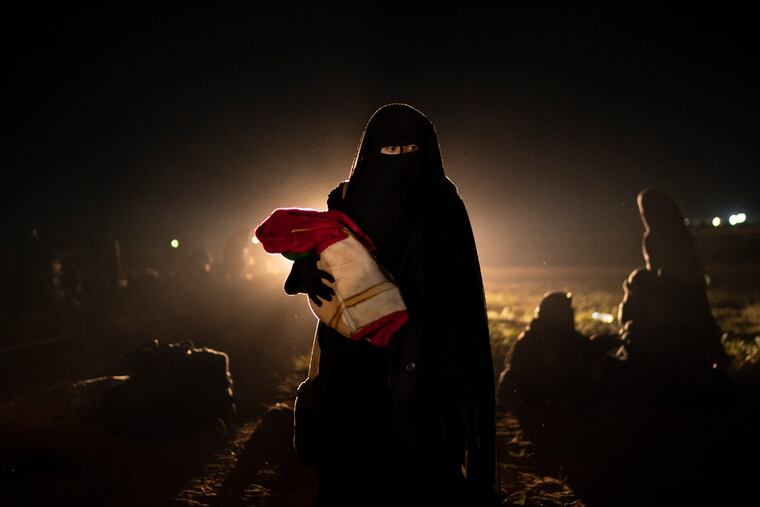 A woman who was evacuated out of the last territory held by Islamic State militants holds her baby after being screened by U.S.-backed Syrian Democratic Forces (SDF) in the desert outside Baghouz, Syria, Monday, Feb. 25, 2019. (AP Photo/Felipe Dana)