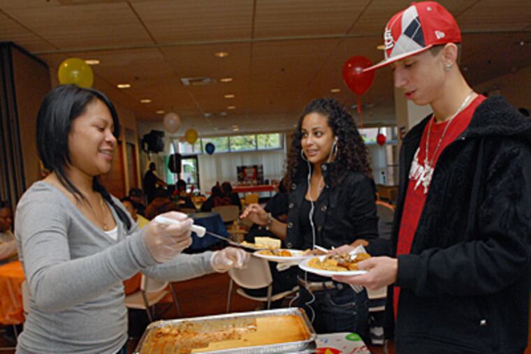 At Camden County College's Camden city campus, a Hispanic Expo in honor of Spanish Heritage Month, including singing, dancing and lots of Hispanic food. Here, Hoanh Thach, left, dishes out food for Millivett Jimenez and James Zamora; all three are Camden County college students. (April Saul / Staff Photographer)