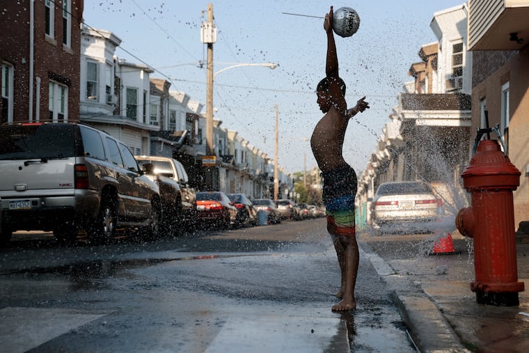 Roman Stanley, 9, plays in water spray from a fire hydrant at the corner of East Cornwall Street and G Street.