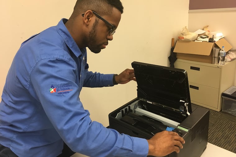 Shabazz Ransom, an IT apprentice, troubleshooting an issue with a printer at his worksite site, Philadelphia Learning Academy North, in March 2018.