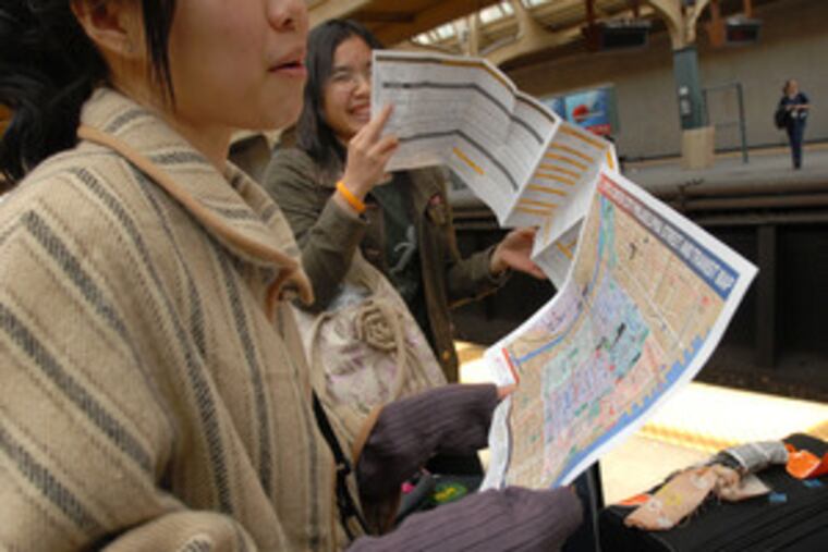 SEPTA's Regional Rail map is studied at 30th Street Station by Patcharee Sriphadungporn (foreground) and Pom Kasorn, two visitors from Thailand. Fare structures and transfers could be altered significantly under two scenarios.
