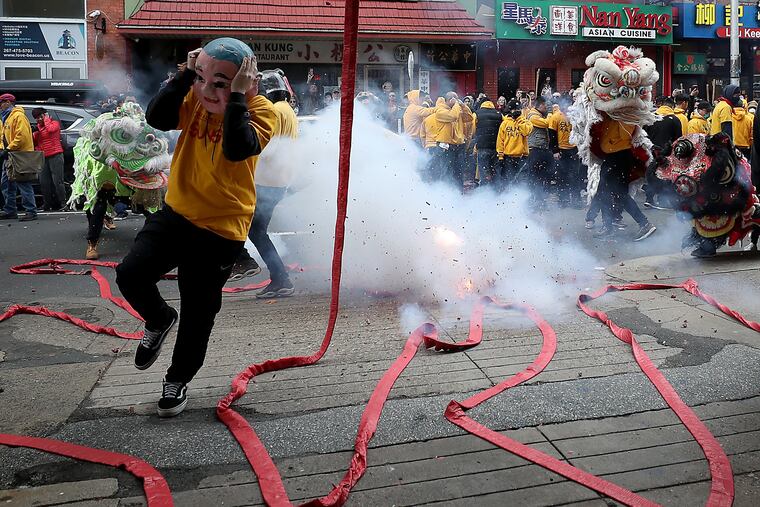 A dancer from the Philadelphia Suns Lion Dance troupe jumps over a string of firecrackers during the Chinese Lunar New Year celebration in Philadelphia.