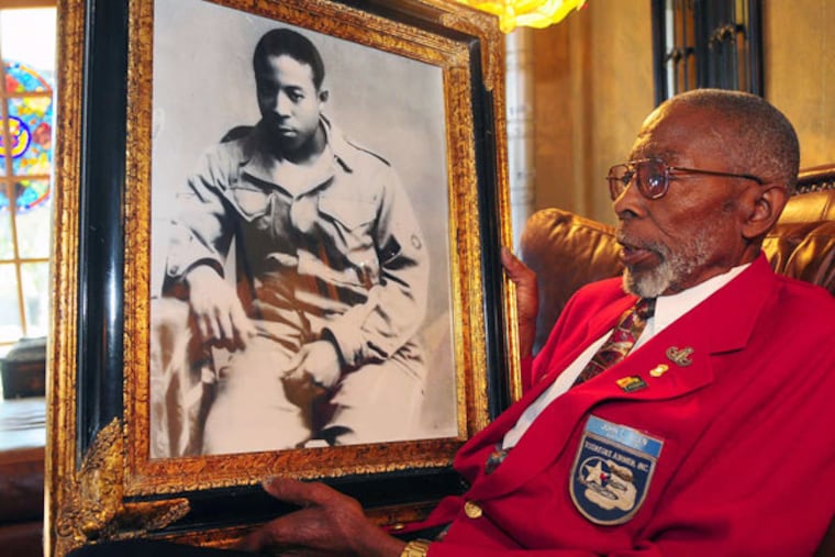 Tuskegee Airman John Edward Allen holds a photo last year of him in his early 20s. Allen died earlier this week at age 84. (Associated Press)