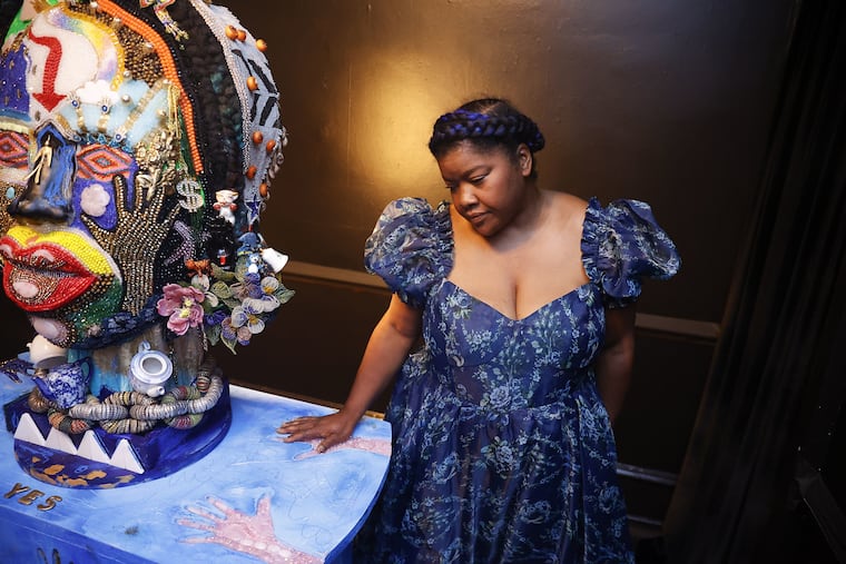 At the Colored Girls Museum, vanessa german stands next to "The Oracle" and "The Table," two characters in her exhibit "The House, The Oracle and The Table."
