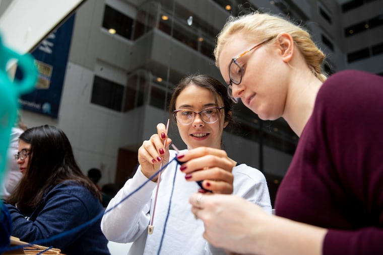 First-year medical students Mary Metkus (left), 22, of Malvern, and Brianna Kunes, 22, of DuBois, Pa., learn to knit and crochet during wellness week at Thomas Jefferson University Hospital last month.