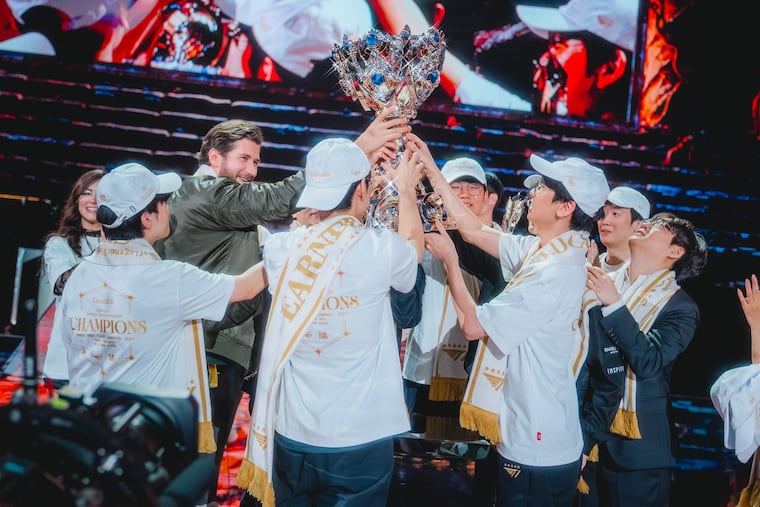 T1's League of Legends team, along with Comcast Spectacor chief innovation officer Tucker Roberts (second from left), raises the Summoner's Cup after winning its third consecutive world championship.