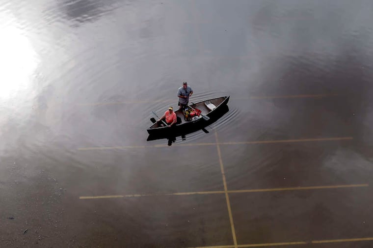 In Houston, people prepare to paddle a canoe from a flooded parking lot.