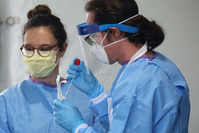Stephen Bonett, a nurse and Philadelphia Medical Reserve Corps volunteer, places a completed nasal swab into a vial at the city's coronavirus testing site next to Citizens Bank Park in South Philadelphia on Friday, March 20, 2020.