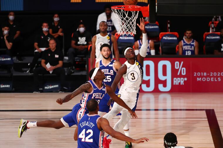 Indiana Pacers guard Aaron Holiday (3) shoots next to 76ers guard Shake Milton.