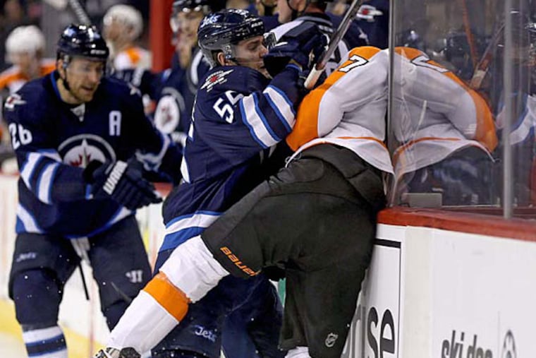 Winnipeg Jets' Mark Scheifele (55) hits Philadelphia Flyers' Wayne Simmonds (17) into the Jets' bench during the second period of an NHL hockey game, Sunday, Dec. 21, 2014 in Winnipeg, Manitoba. (AP Photo/The Canadian Press, Trevor Hagan)
