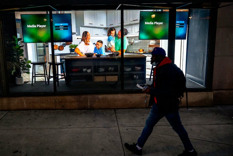 April 18, 2022: A life-size, picture-perfect advertisement family and not-so perfect technology combine in a display window of a retailer on Market Street East.