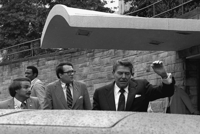 President Ronald Reagan winces and raises his left arm as he was shot by an assailant as he left a Washington hotel, Monday, March 30, 1981.