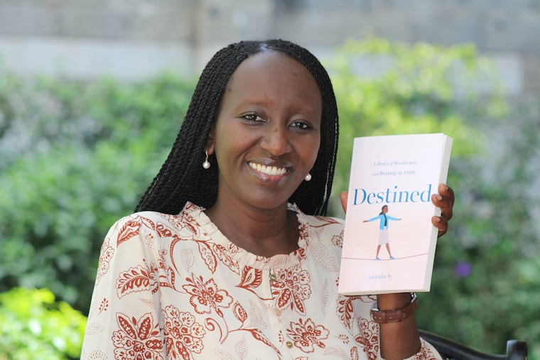 Aminata Sy holds the book she self published, documenting her journey from high school dropout to Ivy League graduate and a career as an American diplomat.