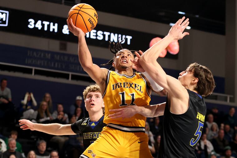 Jason Drake, center, of Drexel goes up for a shot against Macon Emory of Delaware during the first half on Jan. 25, 2025 in a CAA rivalry game.