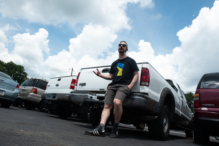 Roman Strakovsky leans against a Ford F-250 truck at Brothers Auto Center in Clayton on July 15, 2023. Strakovsky is raising money to ship the vehicle over 4,000 miles to aid Ukrainian forces against the Russian invasion.