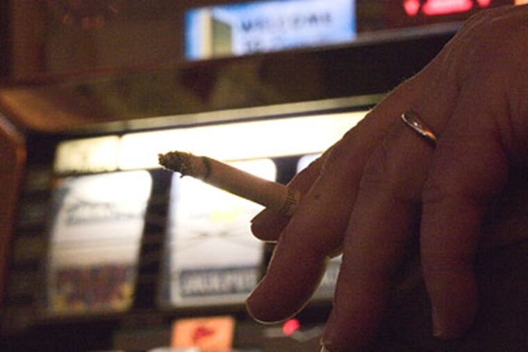 Dave Stout, of Barnegat, plays a slot machine and smokes at the Borgata Casino in Atlantic City. (David M Warren / Staff Photographer)