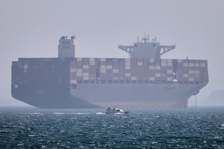 A container ship sits at anchor as a small motorboat passes in the foreground in the Strait of Hormuz off Bandar Abbas, Iran, Saturday, May 2, 2026.