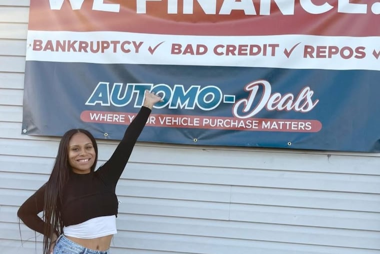 Tianna Williams next to the sign of her car dealership in Easton.