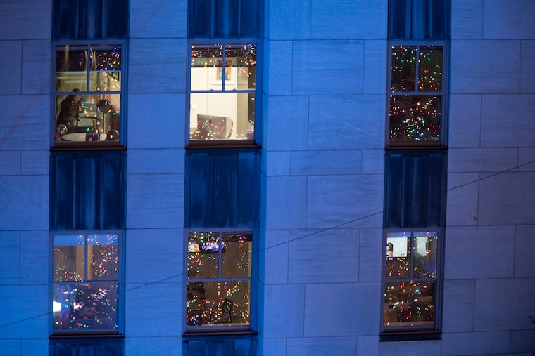 In this Nov. 28, 2018, file photo, people work in their office after the Rockefeller Center Christmas tree is lit during the 86th annual Rockefeller Center Christmas tree lighting ceremony in New York. Holiday staffing is one of a small business owner’s biggest stressors. But giving gifts or bonuses is a way for employees to feel valued. (AP Photo/Mary Altaffer, File)