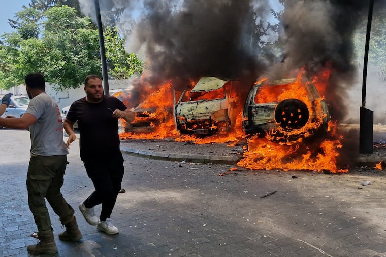 A man runs past burning cars Wednesday following an Israeli airstrike in the southern port city of Sidon, Lebanon.