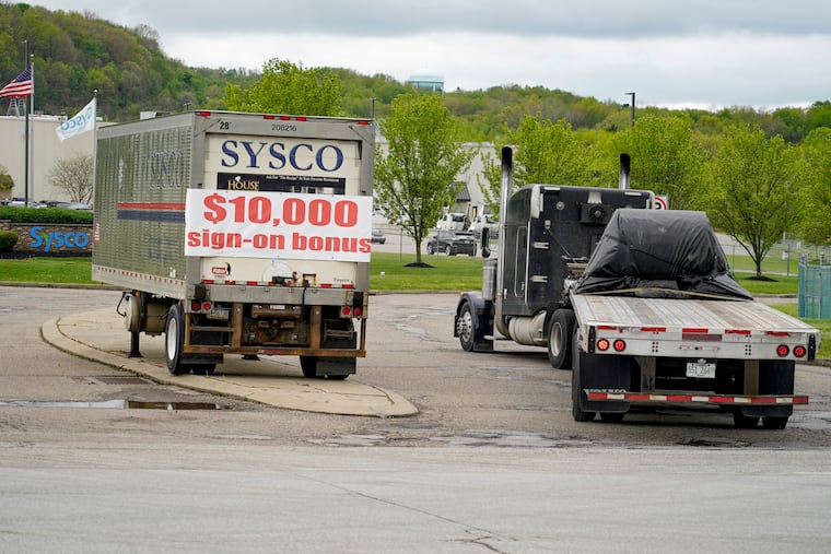 In this 2021 AP file photo, a tractor trailer rig pulls into a terminal for a trucking company that has a $10,000 hiring bonus offer posted on a trailer at their facility in Harmony, Pa.