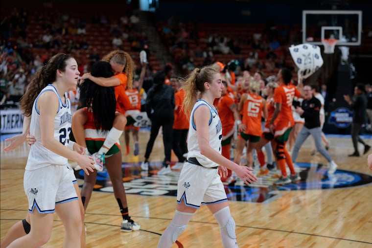 Maddy Siegrist (left) and Lucy Olsen of Villanova walk off the court as Miami celebrates in the background after their win in the Sweet Sixteen NCAA Women's Tournament game in Greenville, South Carolina on March 24, 2023.