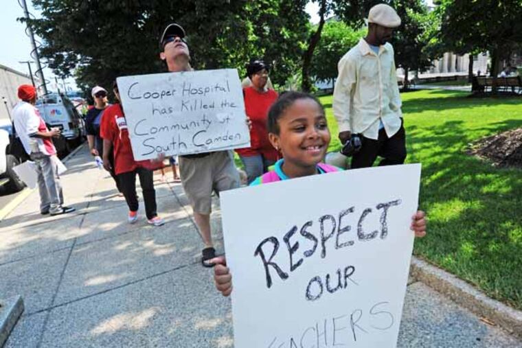 In Camden, NJ, activists protest state takeover of schools and district layoffs on June 25, 2013. Here, Kimonye Mays, 8, carries a sign. ( APRIL SAUL / Staff )