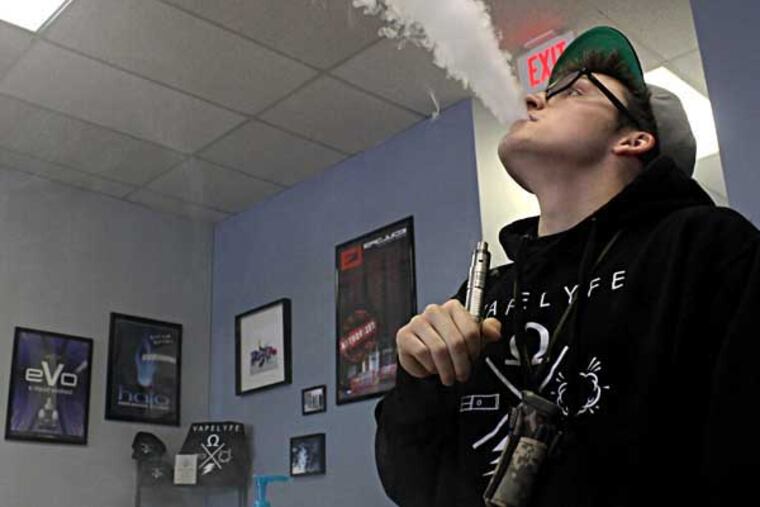 Cole Mentzer, a sales associate at Popie's Vapor Lounge, exhales vapor after taking a drag from his e-cig, in Marlton, New Jersey on Thursday, April 24, 2014. ( COURTNEY MARABELLA / Staff Photographer )