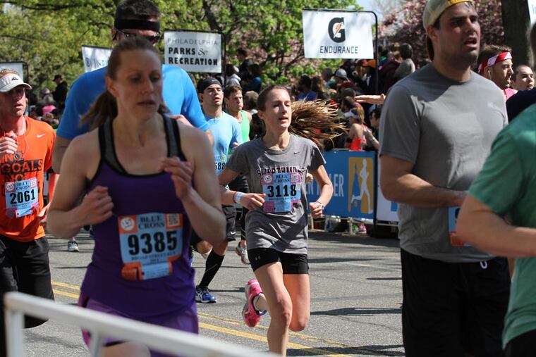 Runners cross the finish line of the Broad Street Run in 2014. In training for such endurance races, the repetitive stress on the feet can wear on the bones and lead to small cracks called stress fractures, which cause pain and swelling. (Stephanie Aaronson/Philly.com)