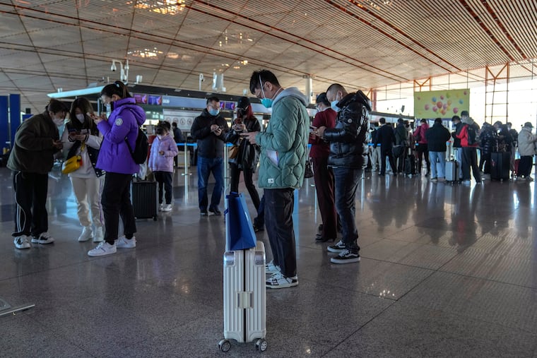 Masked travellers use their smartphones to fill in their health declaration after checking in at the international flight check-in counter at the Beijing Capital International Airport on Thursday.