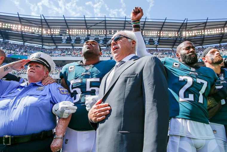 Eagles owner Jeffrey Lurie joins defensive end Brandon Graham (55) and safety Malcolm Jenkins during the national anthem. Jenkins raises his fist as a form of protest.
