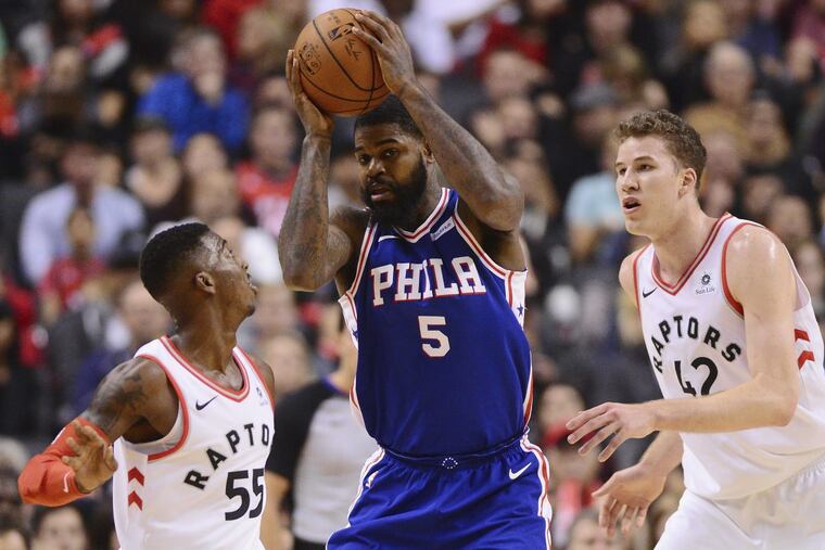 Sixers forward Amir Johnson (5) looks to pass the ball under pressure from Raptors guard Delon Wright (left) and center Jakob Poeltl during Saturday’s game in Toronto.