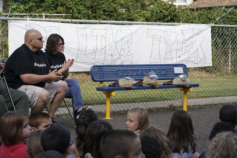 Mark and Lori Quinter look on as teachers and students participate in a dedication ceremony for the Tyler Quinter “buddy bench.”