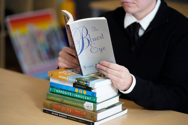 Amanda Darrow, director of youth, family, and education programs at the Utah Pride Center, poses with books, including "The Bluest Eye" by Toni Morrison, that have been the subject of complaints from parents across the country.