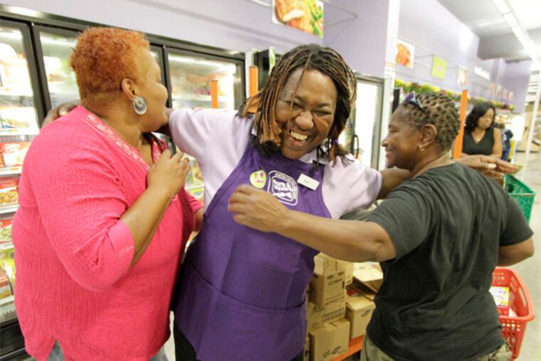 Fare & Square employee Sonia Rollins (center) hugs friends who were shopping at Saturday's grand opening.