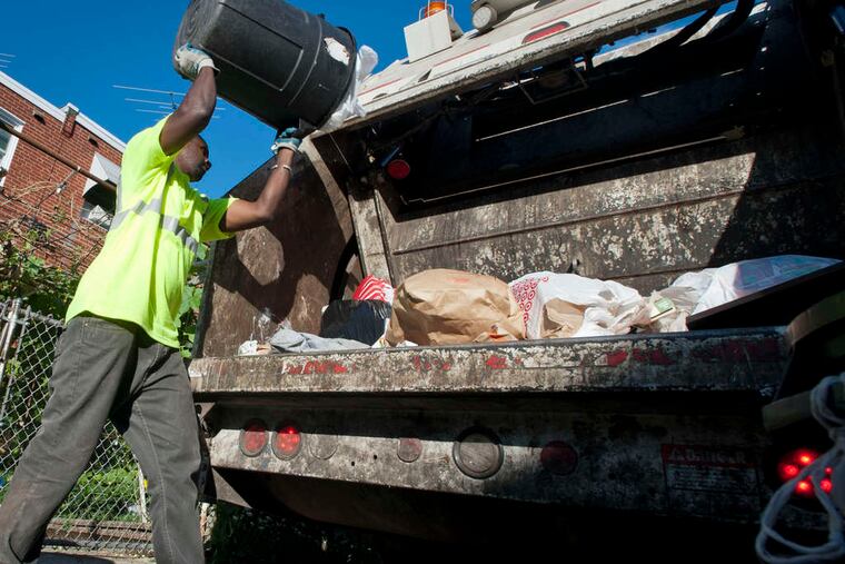 Philadelphia trash collector Mamadou Sacko empties a trash can on a route in the Northeast in 2018.