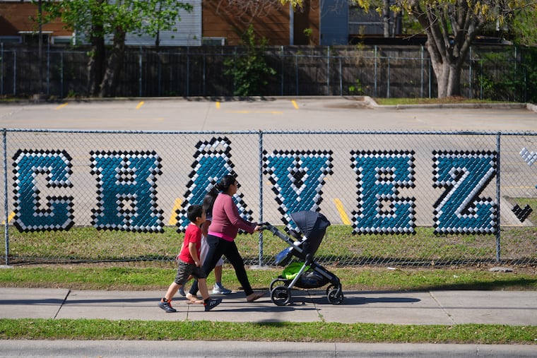 Pedestrians walk past the parking lot of the Cesar Chavez Learning Center in Dallas, March 19, 2026.