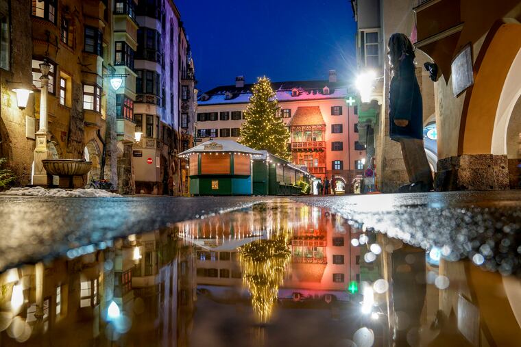 The Christmas tree of the closed Christmas market is reflected in a puddle in Innsbruck, Austria, on Monday.